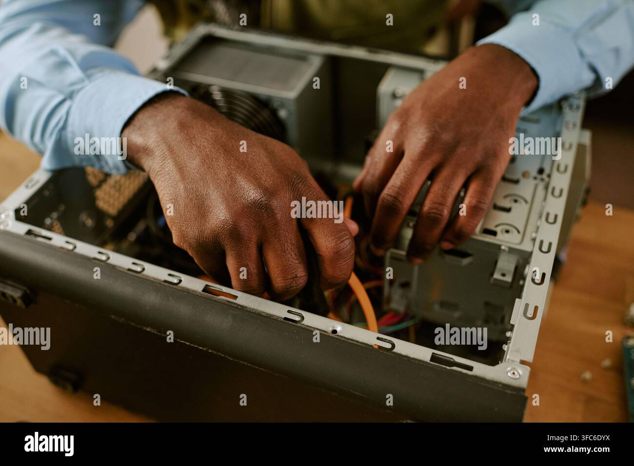 Mani di un uomo nero che ripara un computer retrò in ufficio Foto Stock