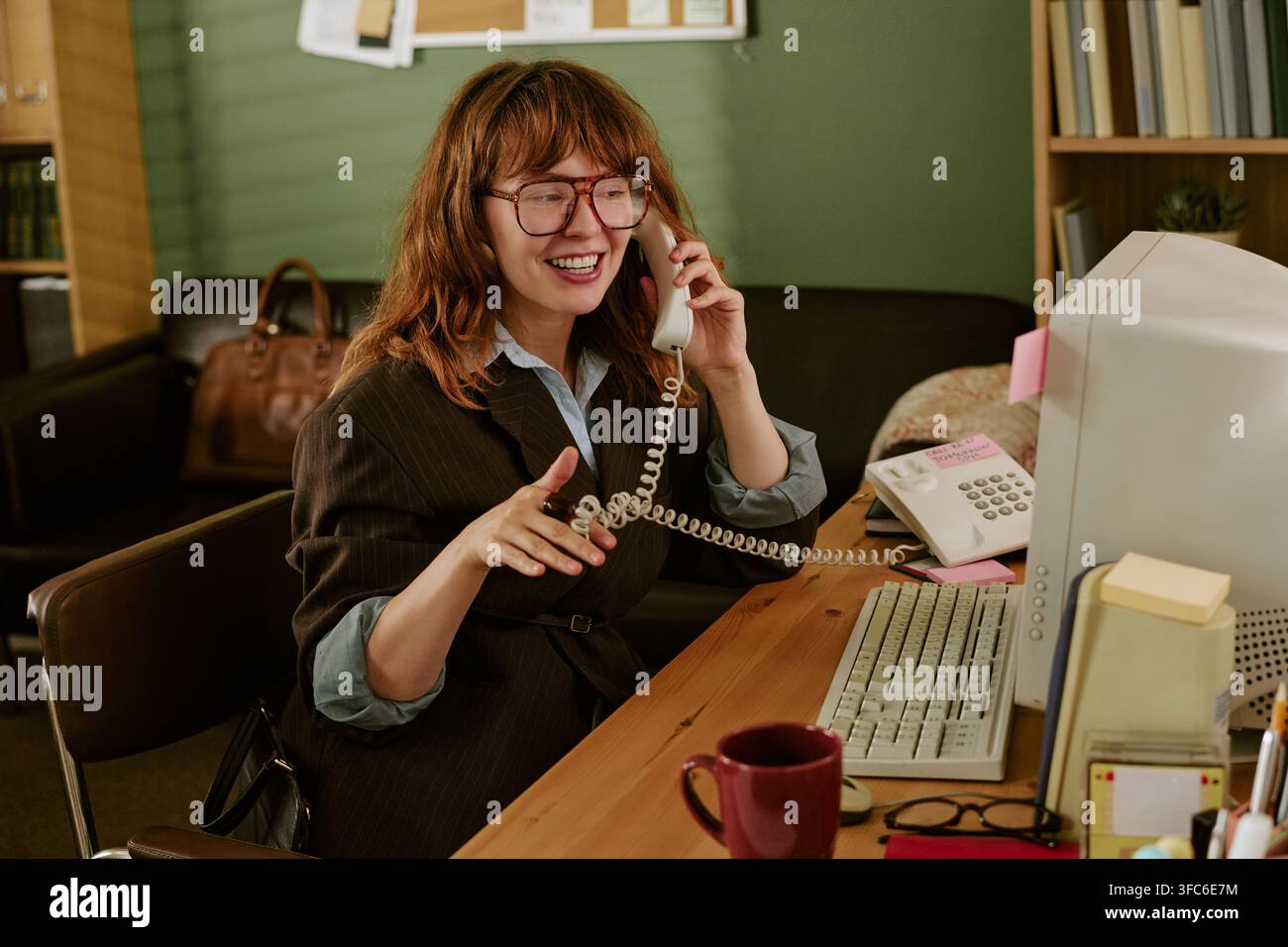 Donna sorridente al telefono in un ufficio retrò Foto Stock