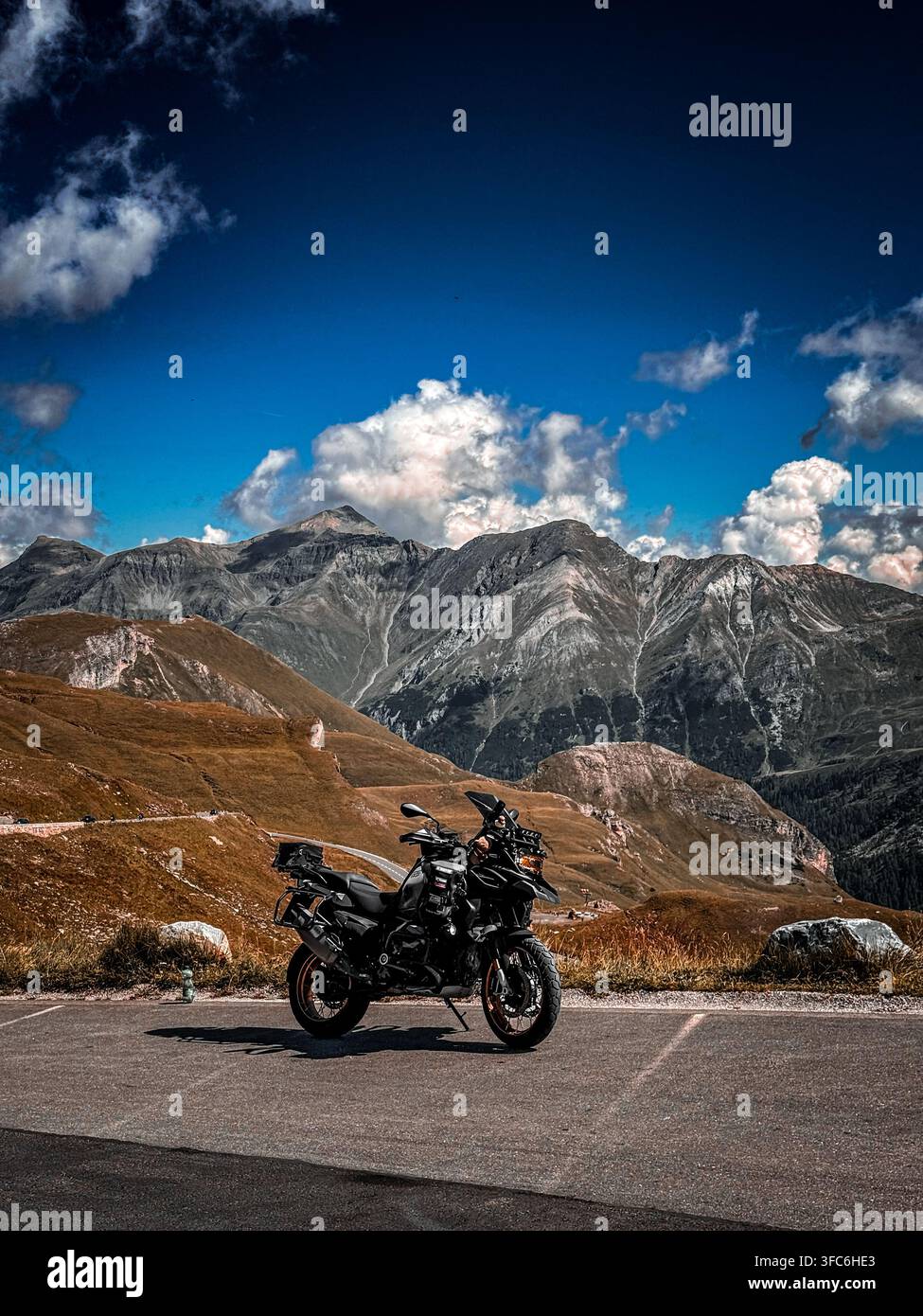 Moto avventura parcheggiata su una strada di montagna con picchi drammatici nelle Alpi austriache - Immagine stock catturata con smartphone