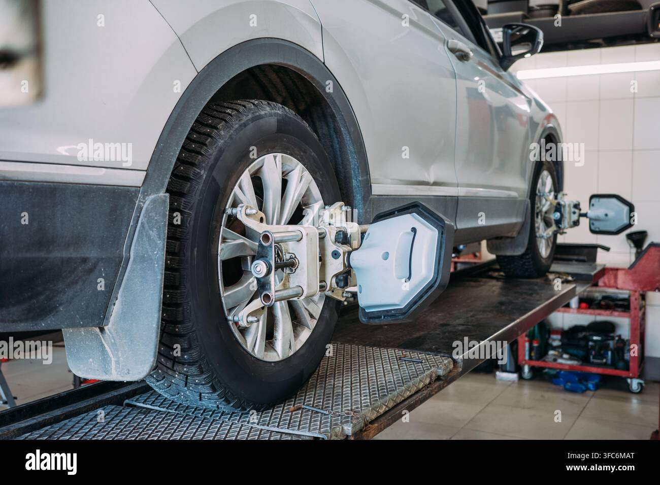 Cambio stagionale delle gomme e allineamento delle ruote per SUV crossover, veicolo su ponte sollevatore in officina con sensori, preparazione per la guida invernale, servizio di manutenzione e impostazione della sospensione. Foto Stock