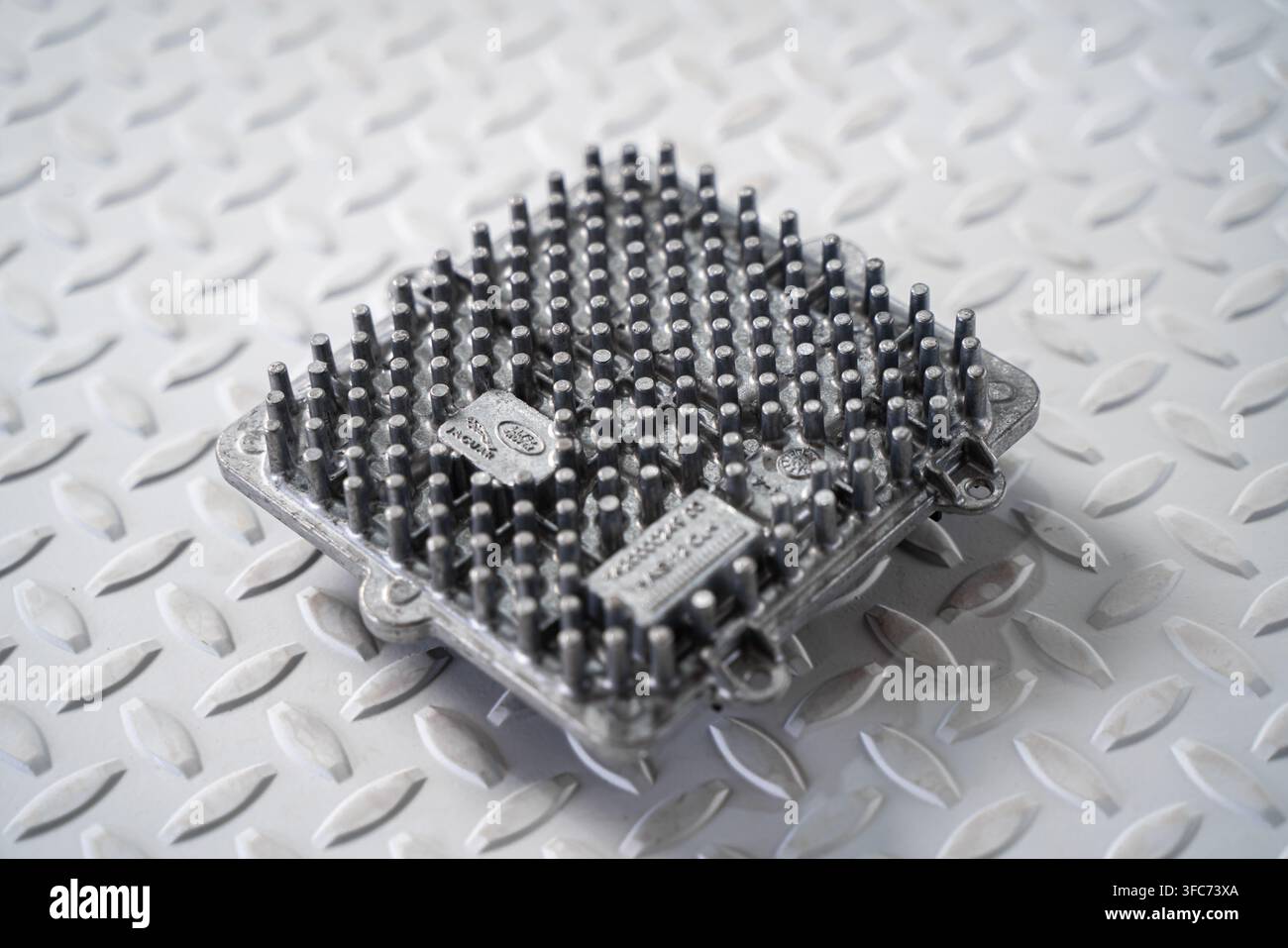 Un modulo di controllo dei fari a LED per autoveicoli con dissipatore di calore in metallo è isolato su uno sfondo studio bianco. Foto Stock