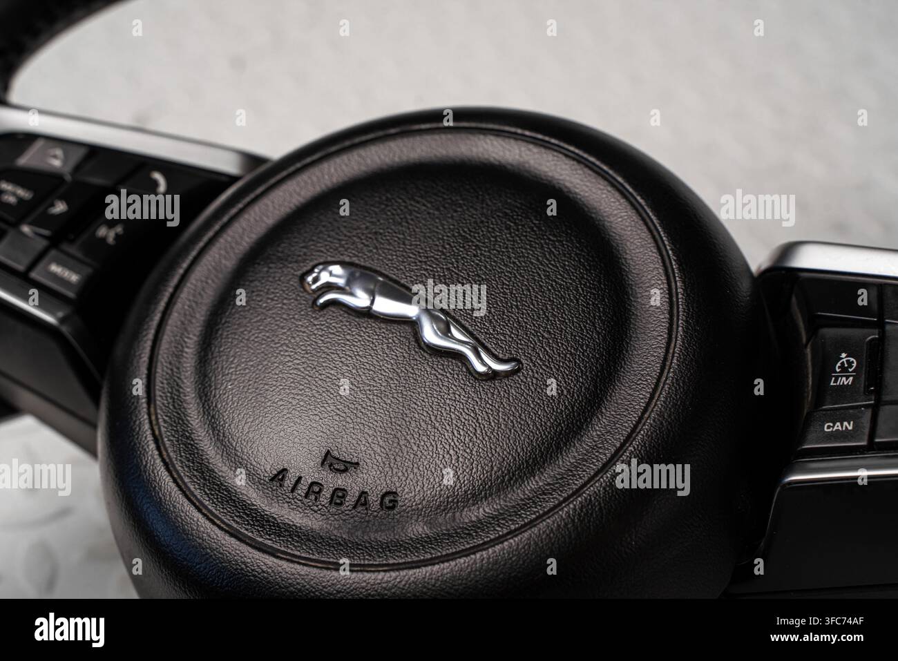 Close up di un airbag del volante Jaguar con l'emblema del produttore e i pulsanti di controllo multifunzione. Foto Stock