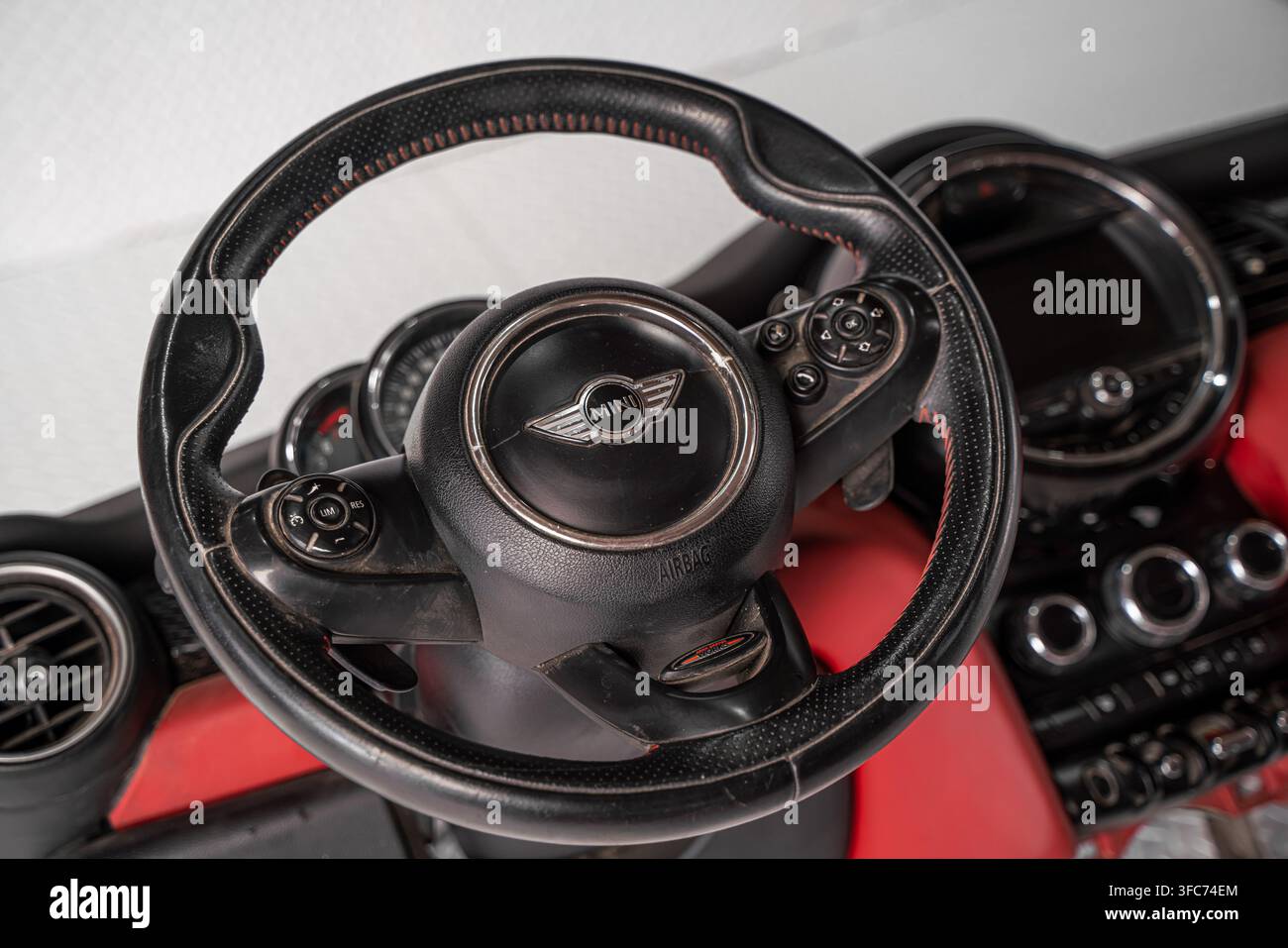 Prima vista di un volante con marchio MINI Cooper installato in un interno del cruscotto automobilistico rosso e nero. Foto Stock