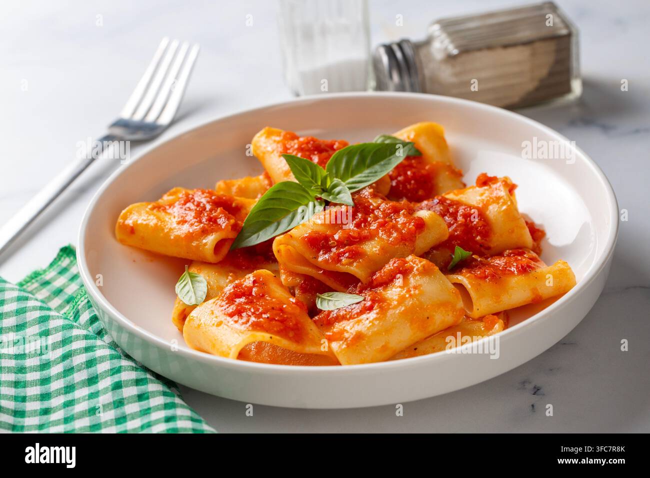 Pasta Paccheri italiana tradizionale con salsa di pomodoro e basilico fresco su sfondo rustico Foto Stock