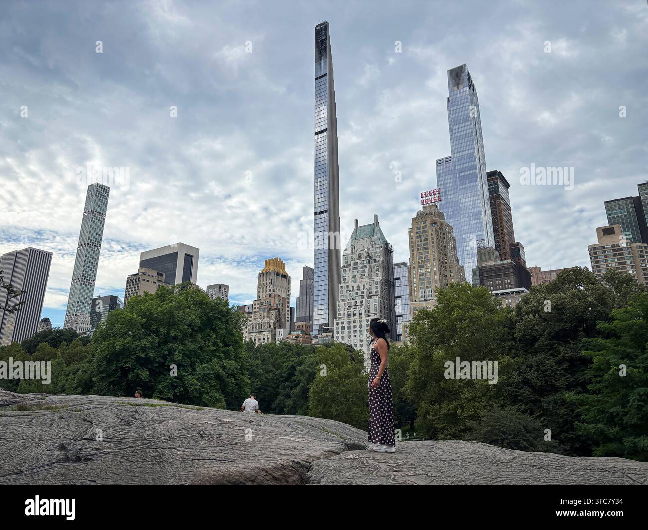 Un visitatore si trova sulle rocce, in controluce contro lo skyline di Midtown. New York, New York, Stati Uniti, 5 agosto 2026. Foto Stock