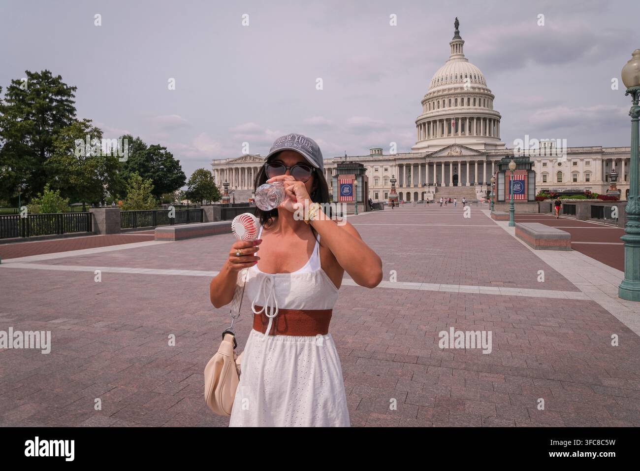 Un visitatore beve acqua e tiene un ventaglio portatile sull'esplanade del Campidoglio degli Stati Uniti. Washington, District of Columbia, Stati Uniti, 12 agosto Foto Stock