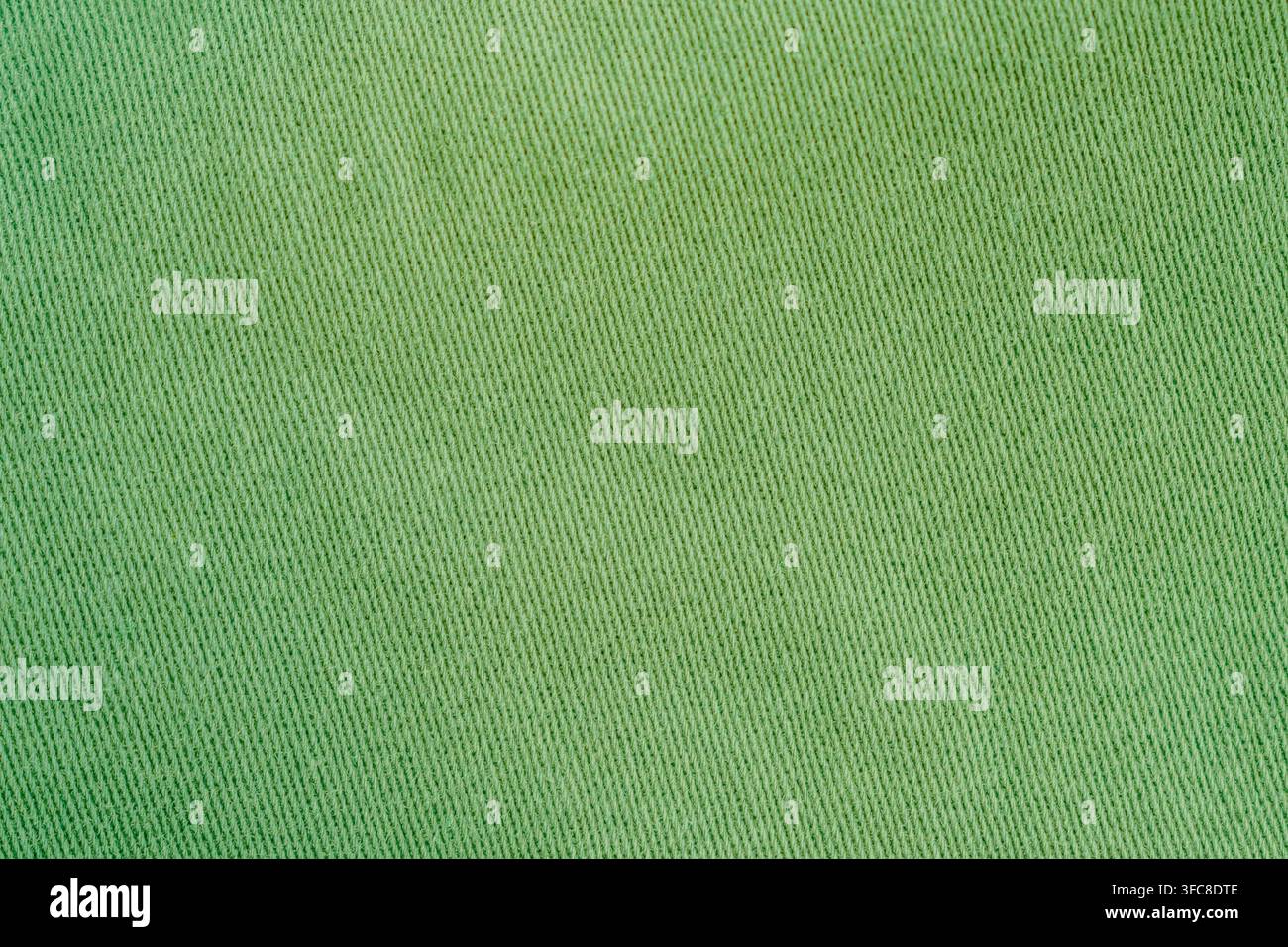 Vista a tutta cornice dall'alto di tessuto di cotone twill verde chiaro piatto con motivo a trama diagonale orizzontale, foto d'archivio. Foto Stock