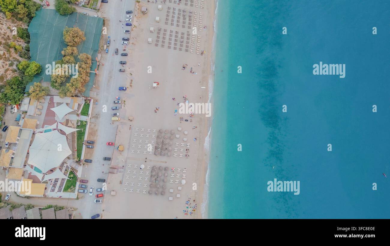 Vista aerea dall'alto della spiaggia di Kathisma con costa turchese, sedie a sdraio, ombrelloni, parcheggio e club sulla spiaggia a Lefkada, Grecia, orizzontale s Foto Stock