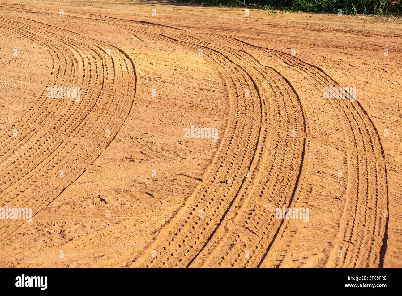 Binari paralleli di camion su una strada sterrata rossa con vegetazione verde rigogliosa sullo sfondo Foto Stock