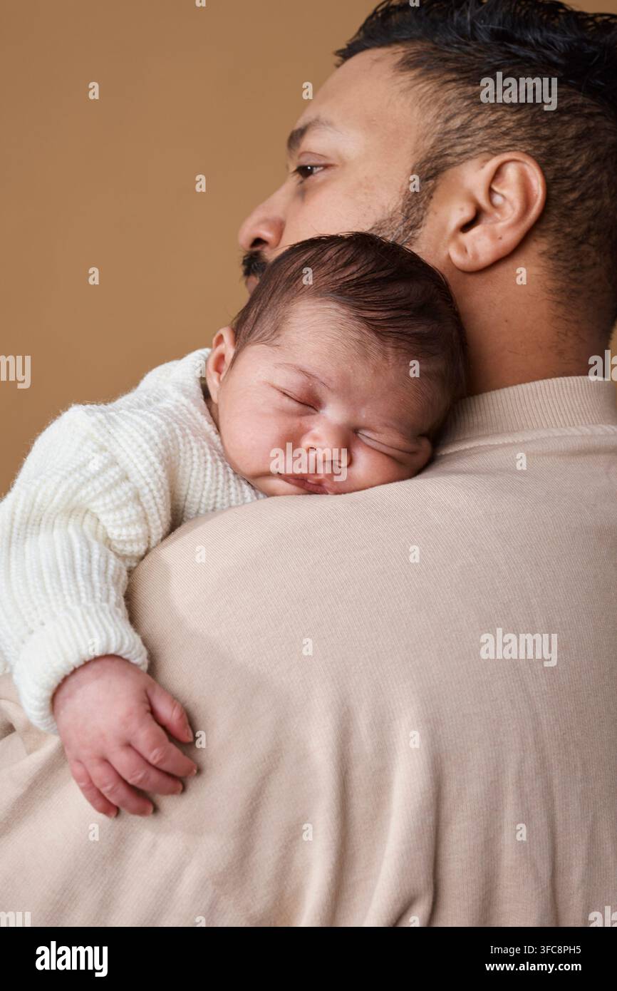 Padre che tiene un neonato addormentato sulla spalla - Legame familiare tenero e momento di genitorialità gentile Foto Stock