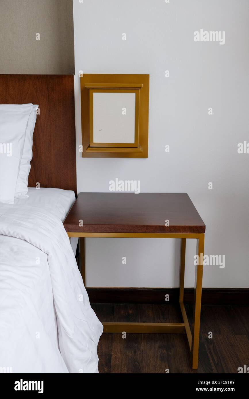 Moderno comodino in legno e tavolo da notte in un interno di camera d'albergo Foto Stock