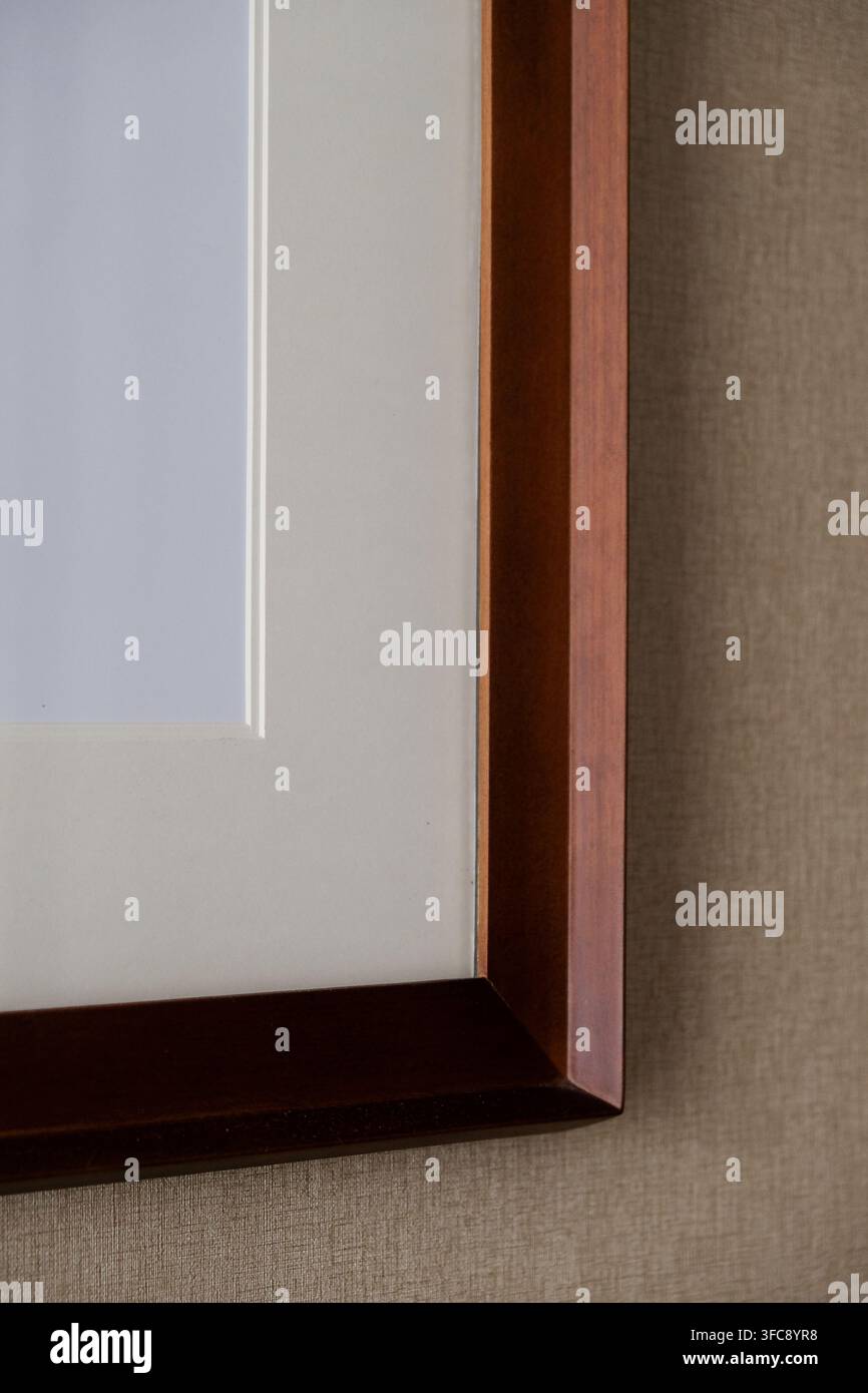 Prima vista di una cornice in legno scuro con passepartout bianco su un muro ruvido Foto Stock