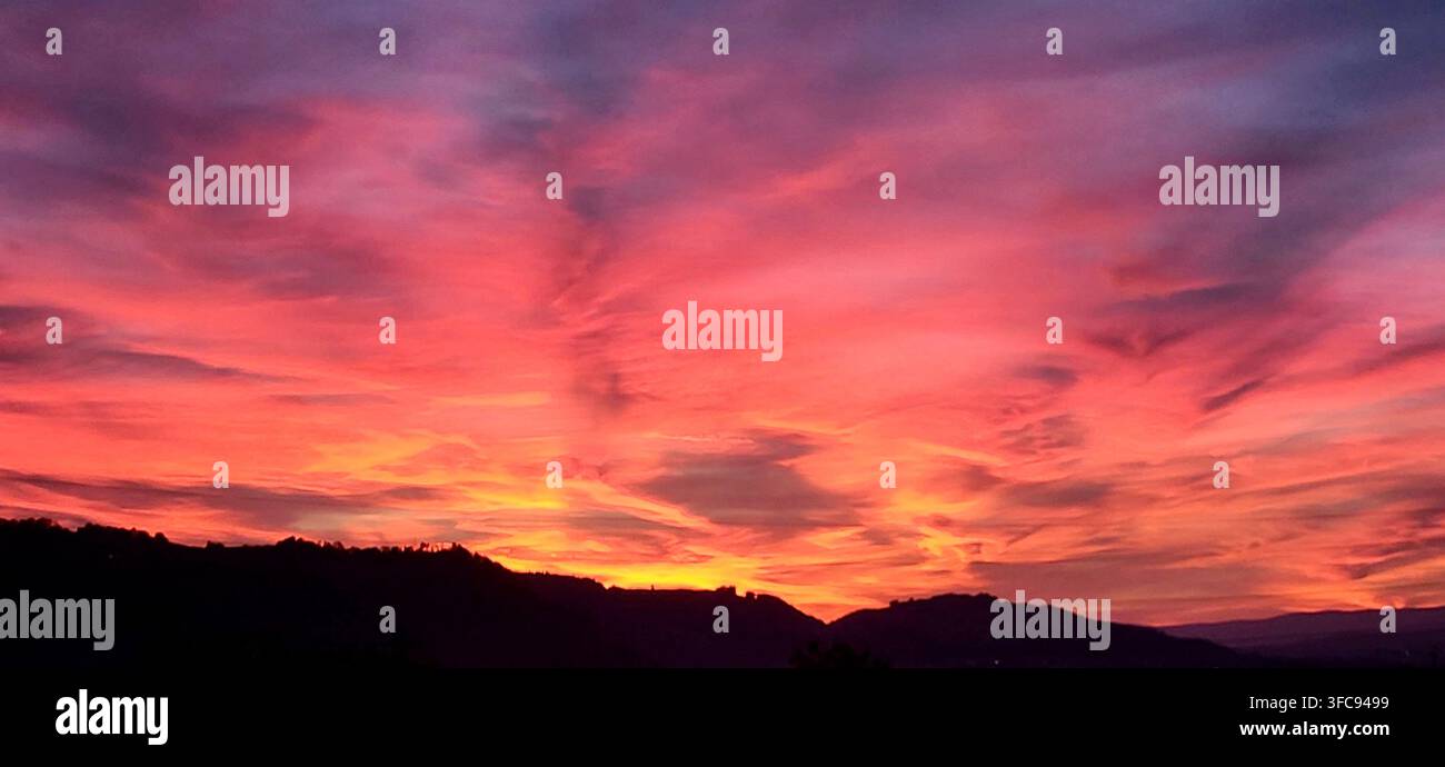 Cielo mattutino pittoresco con toni gialli, arancioni e rosa vibranti su tutto il cielo in Svizzera Foto Stock