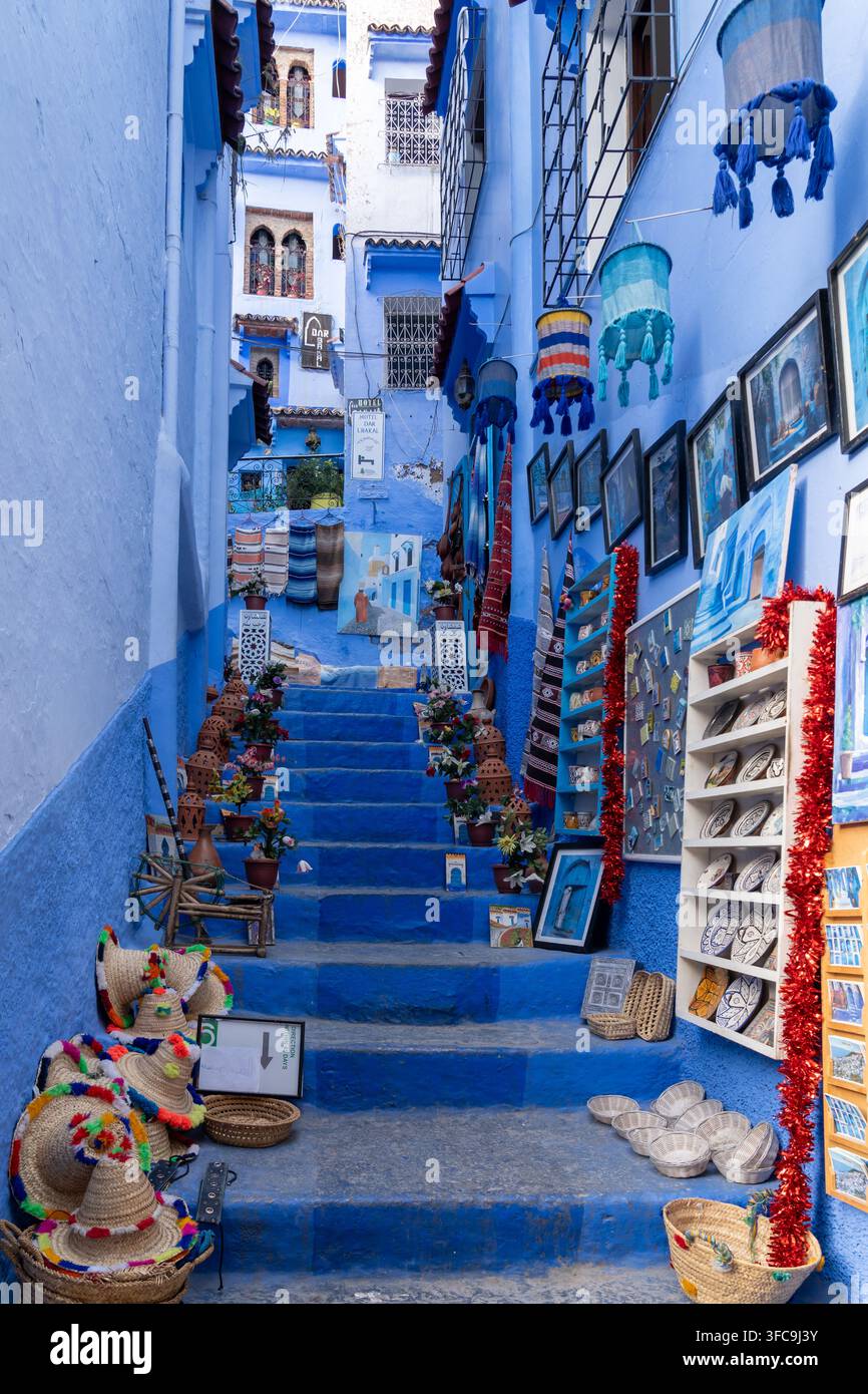 Case e scale colorate di blu con souvenir turistici esposti in vendita a Chefchaouen, Marocco. Foto Stock