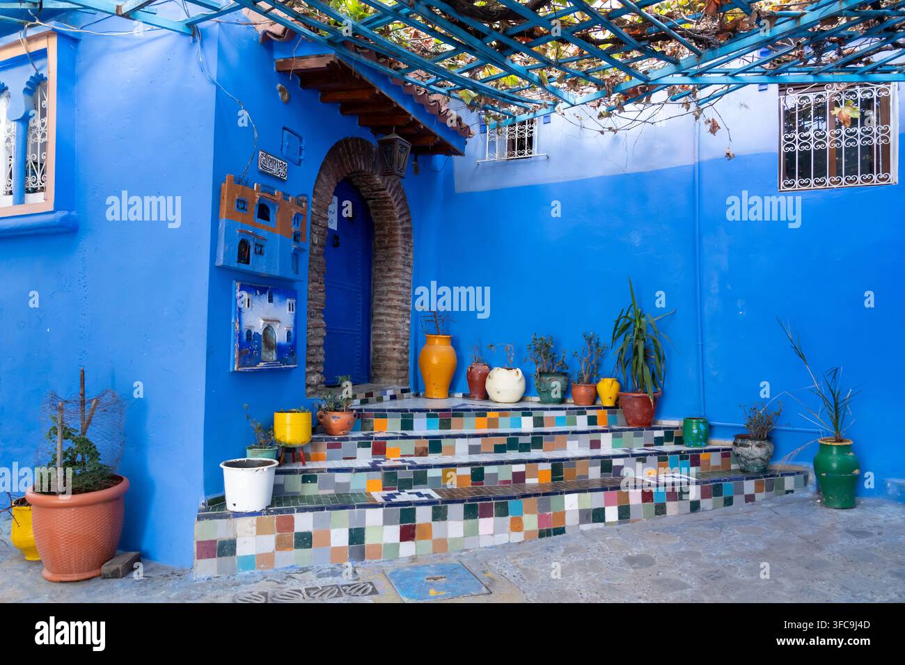 Case blu con gradini colorati e vasi di fiori a Chefchaouen, Marocco. Foto Stock