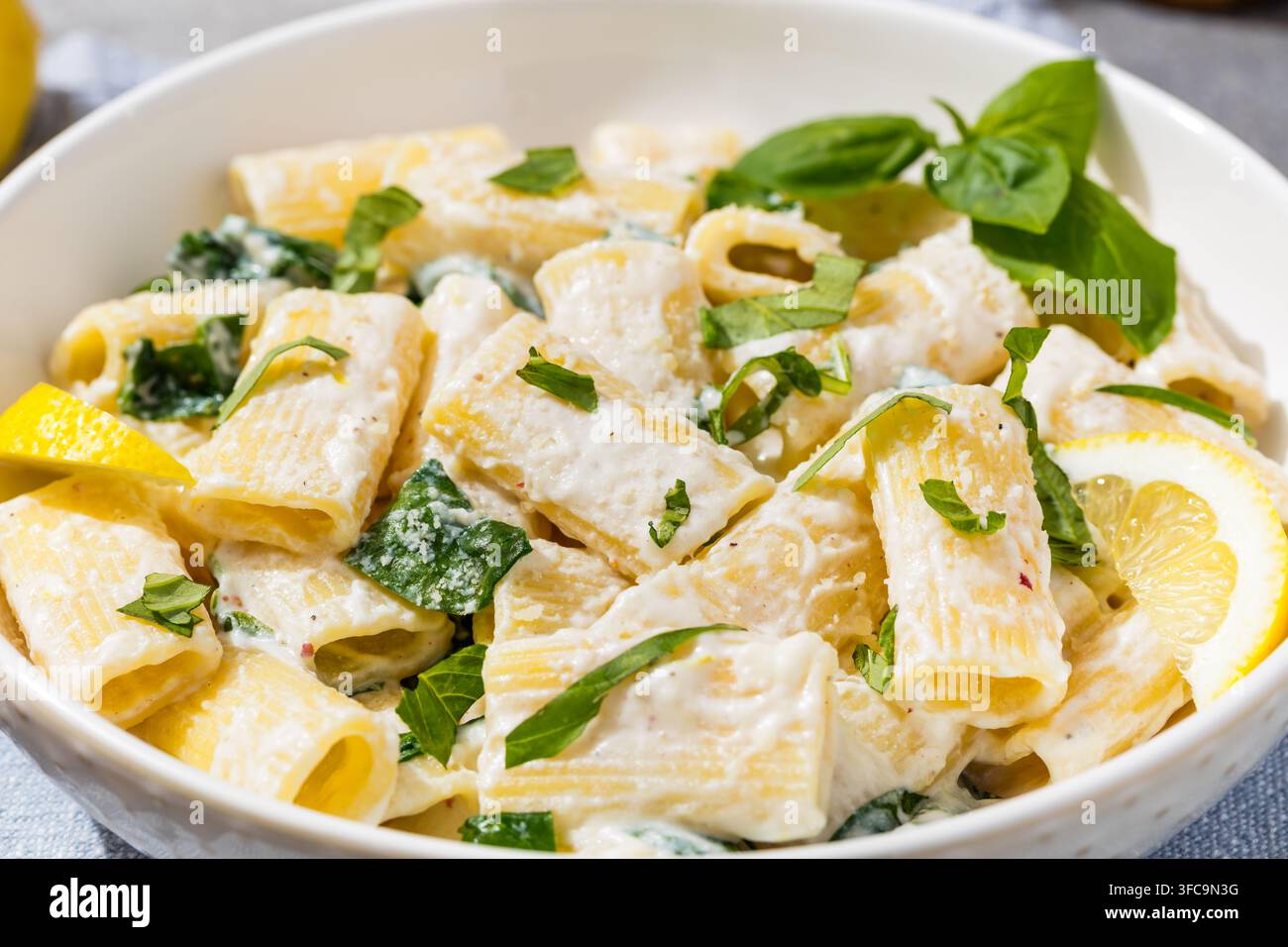 Pasta rigatoni fatta in casa con ricotta al limone saporita, basilico e spinaci Foto Stock
