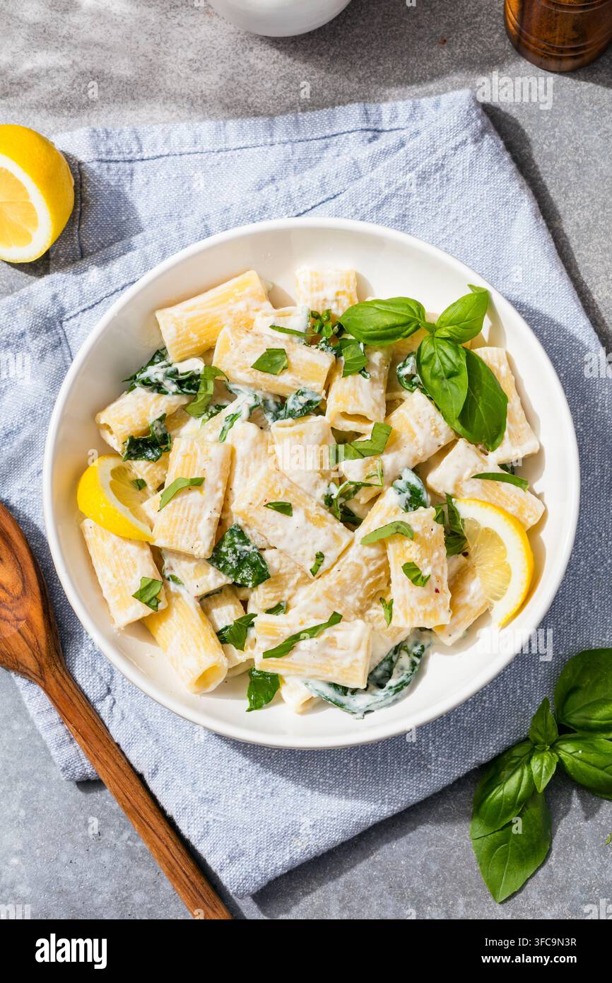 Pasta rigatoni fatta in casa con ricotta al limone saporita, basilico e spinaci Foto Stock