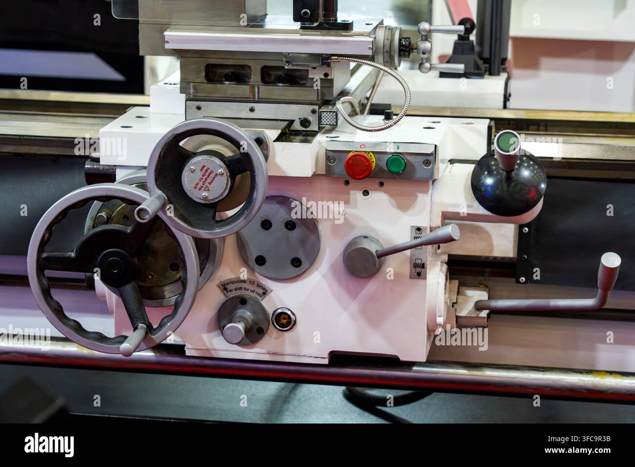 Prima di una macchina tornitura industriale in metallo con volanti di controllo, leve e pulsante di stop di emergenza in officina Foto Stock