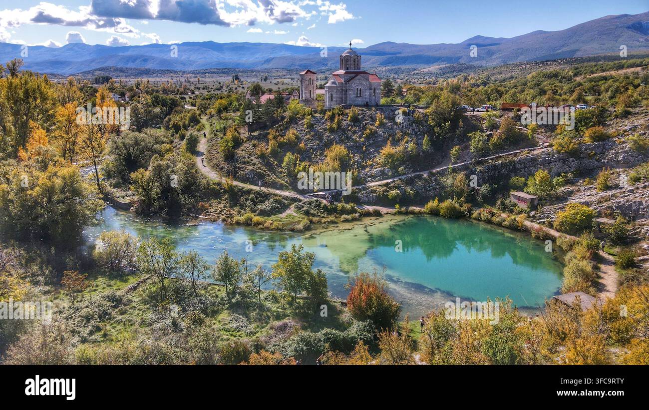Vista aerea della sorgente Eye of the Earth con la sua acqua turchese e la chiesa storica della Santa Salvezza circondata da alberi autunnali a Cetina Foto Stock