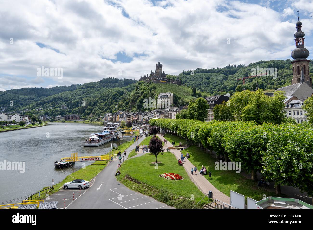 Cochem Germania - 2 ago 25: il castello di Reichsburg Cochem si affaccia sul fiume Mosella, sulle barche, sulla passeggiata e sugli edifici colorati della città in Germania. Foto Stock