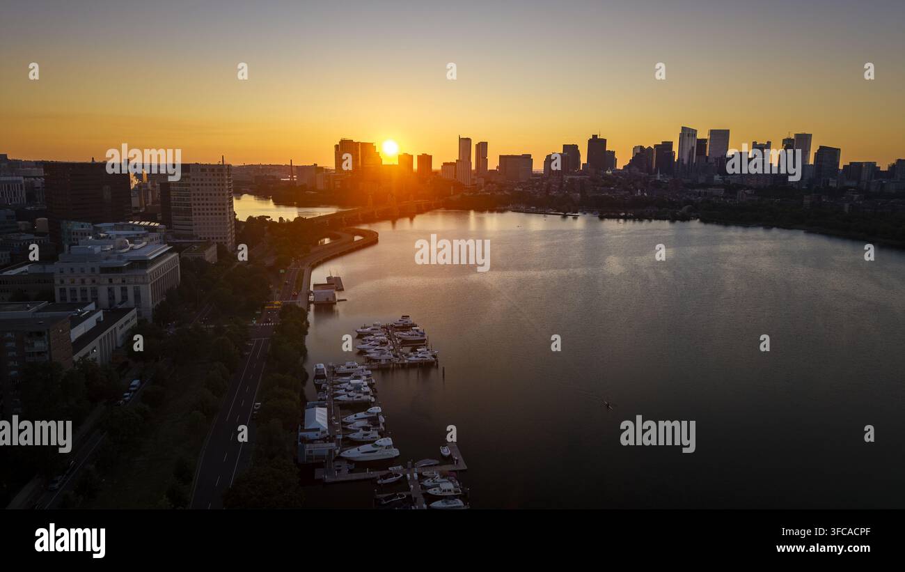 Vista aerea dell'Esplanade del Charles River con barche ormeggiate nel porticciolo e lo skyline di Boston silouettato contro un tramonto vivace a Boston, Mass. Foto Stock