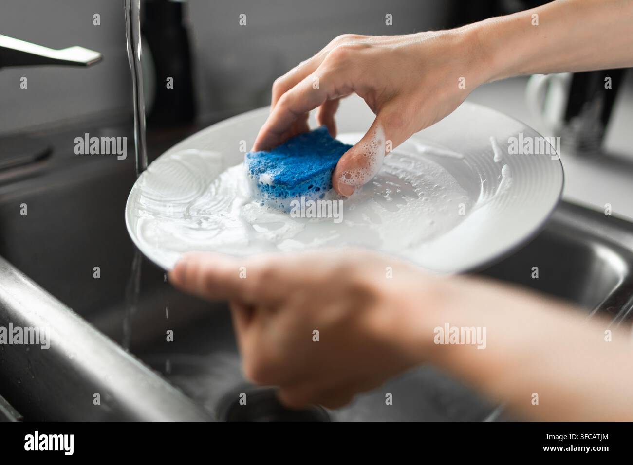 Donna che lavano piatti nel lavandino della cucina. Foto Stock