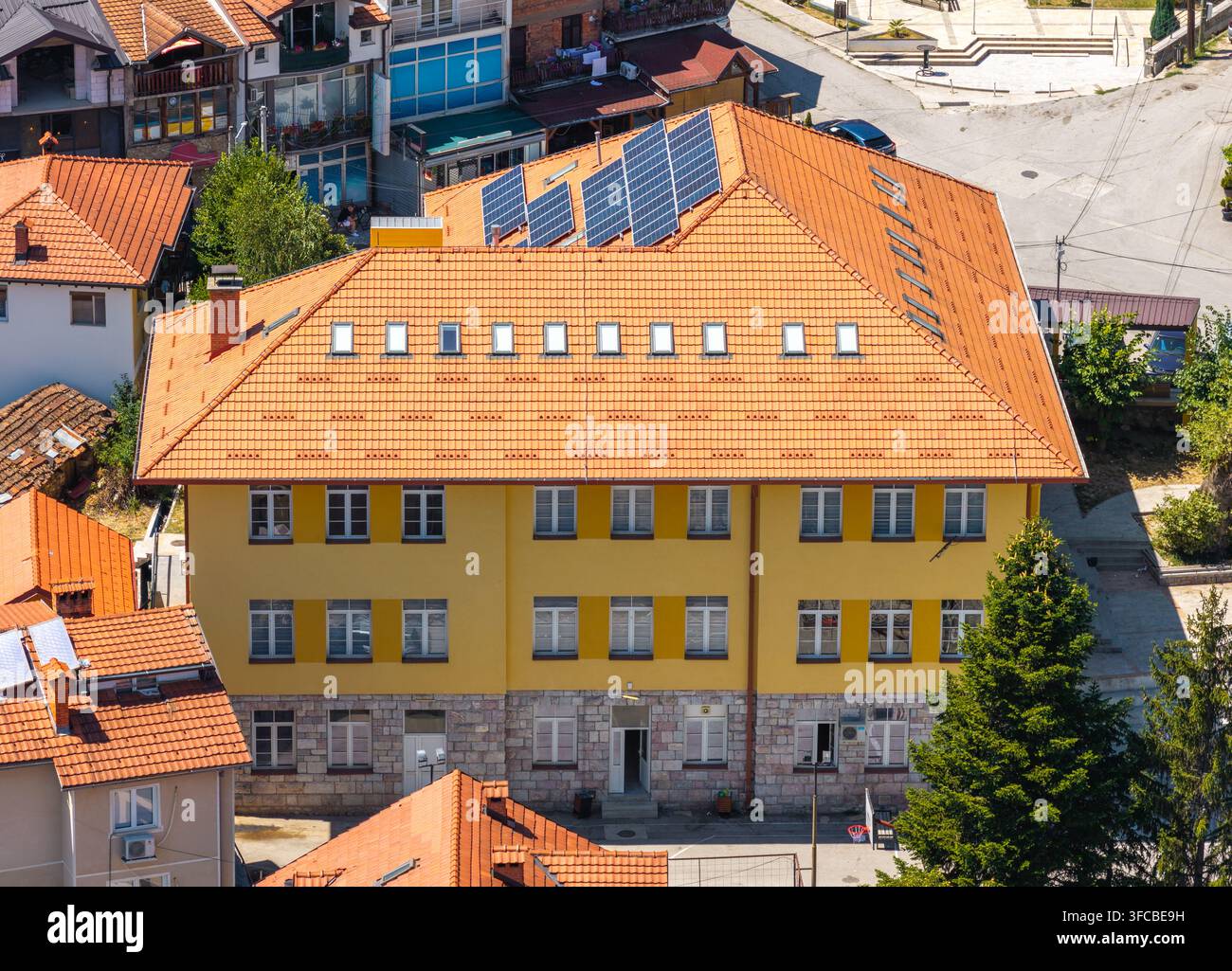 Vista aerea di un edificio giallo con tetto in tegole di terracotta, pannelli solari e fondamenta in pietra a Vevchani, comune di Vevcani, Macedonia del Nord. Foto Stock