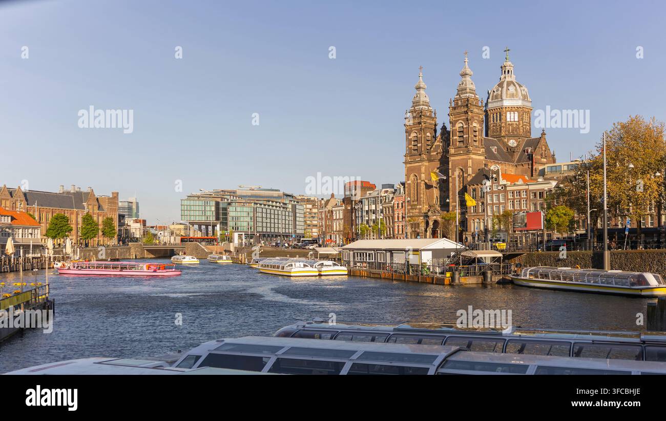 Canali e architettura ad Amsterdam, Paesi Bassi in una giornata di sole con barche che solcano l'acqua. Foto Stock
