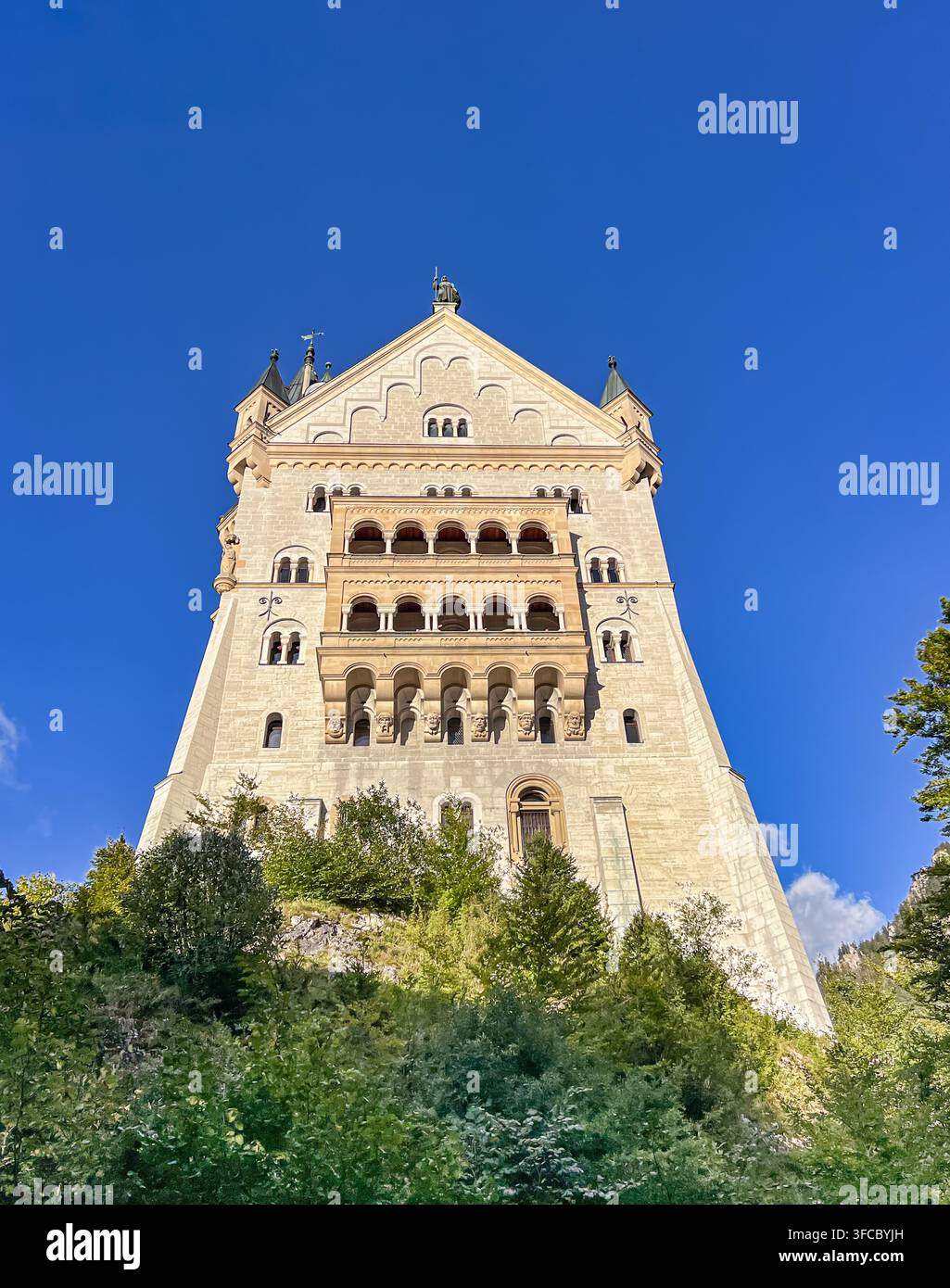 Vista ad angolo basso della facciata ovest ornata e dei balconi dello storico castello di Neuschwanstein contro un cielo blu limpido, Schwangau, Bavaria, Germania Foto Stock