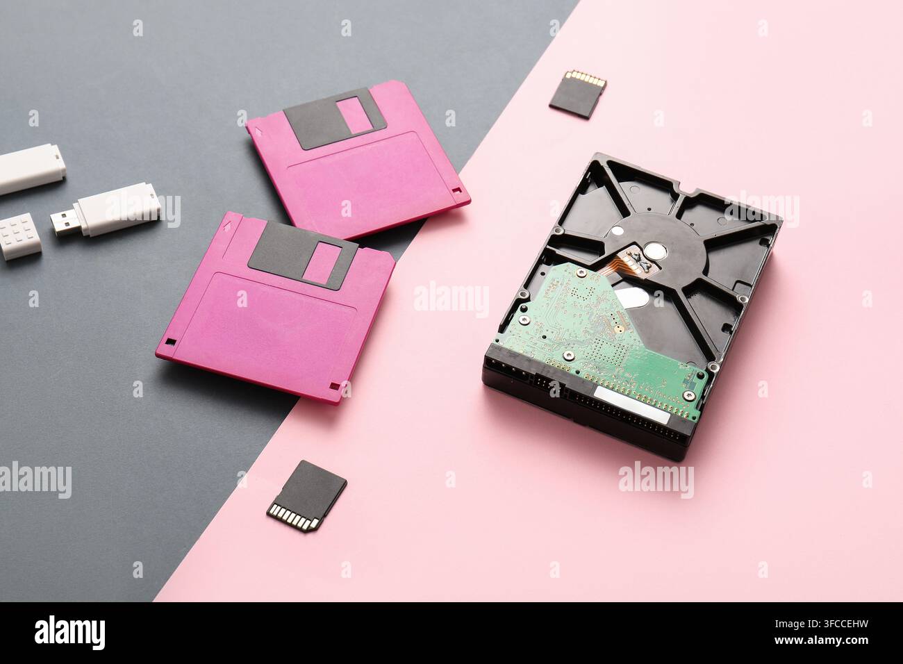 Evoluzione dello storage dei dati e progresso tecnologico: floppy disk, hard drive, chiavetta USB e scheda SD su sfondo diviso Foto Stock