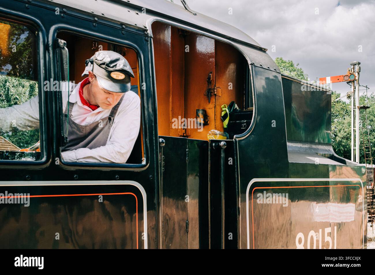 Membro dell'equipaggio della piastra di comando della locomotiva a vapore 80151 alla stazione di Kingscote sulla Bluebell Railway, West Sussex, Inghilterra. Foto Stock