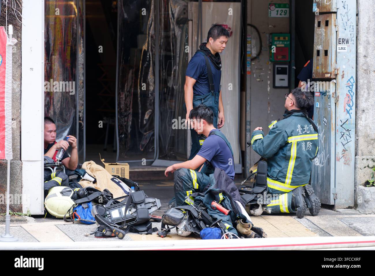 Taipei, Taiwan 2025 agosto 27 Taiwan Vigili del fuoco esausti che si riposano in strada dopo aver spento un incendio in un ristorante a Ximending Foto Stock