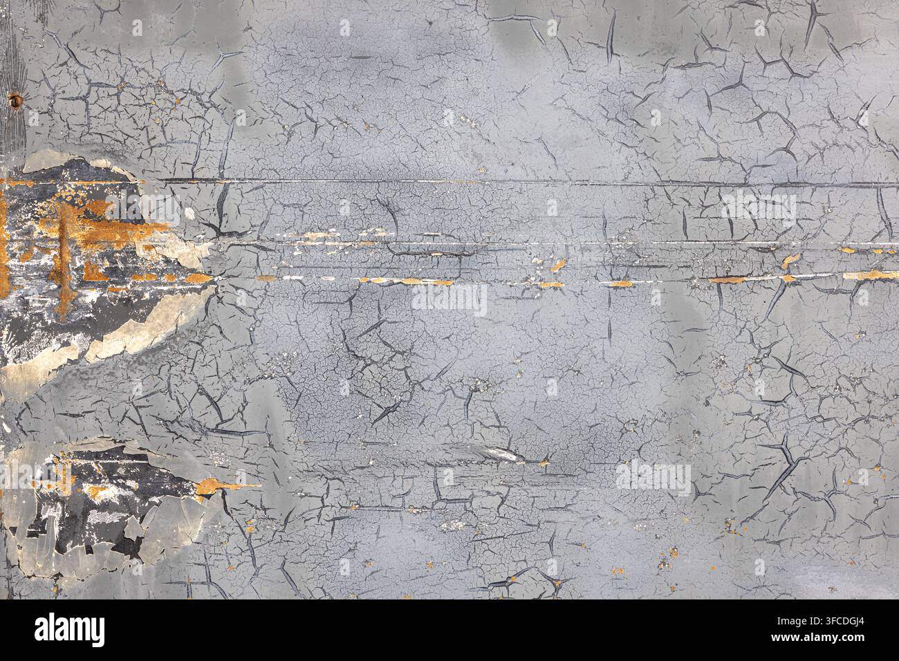 Primo piano di una superficie metallica erosa che mostra vernice grigia scrostata e ruggine. Ampie crepe e scheggiature rivelano strati scuri e una macchia di ruggine arancione Foto Stock