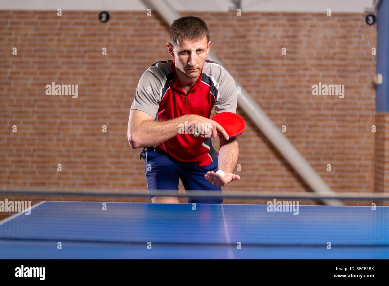 Atleta maschio che tiene una pagaia e una palla prima di servire Foto Stock