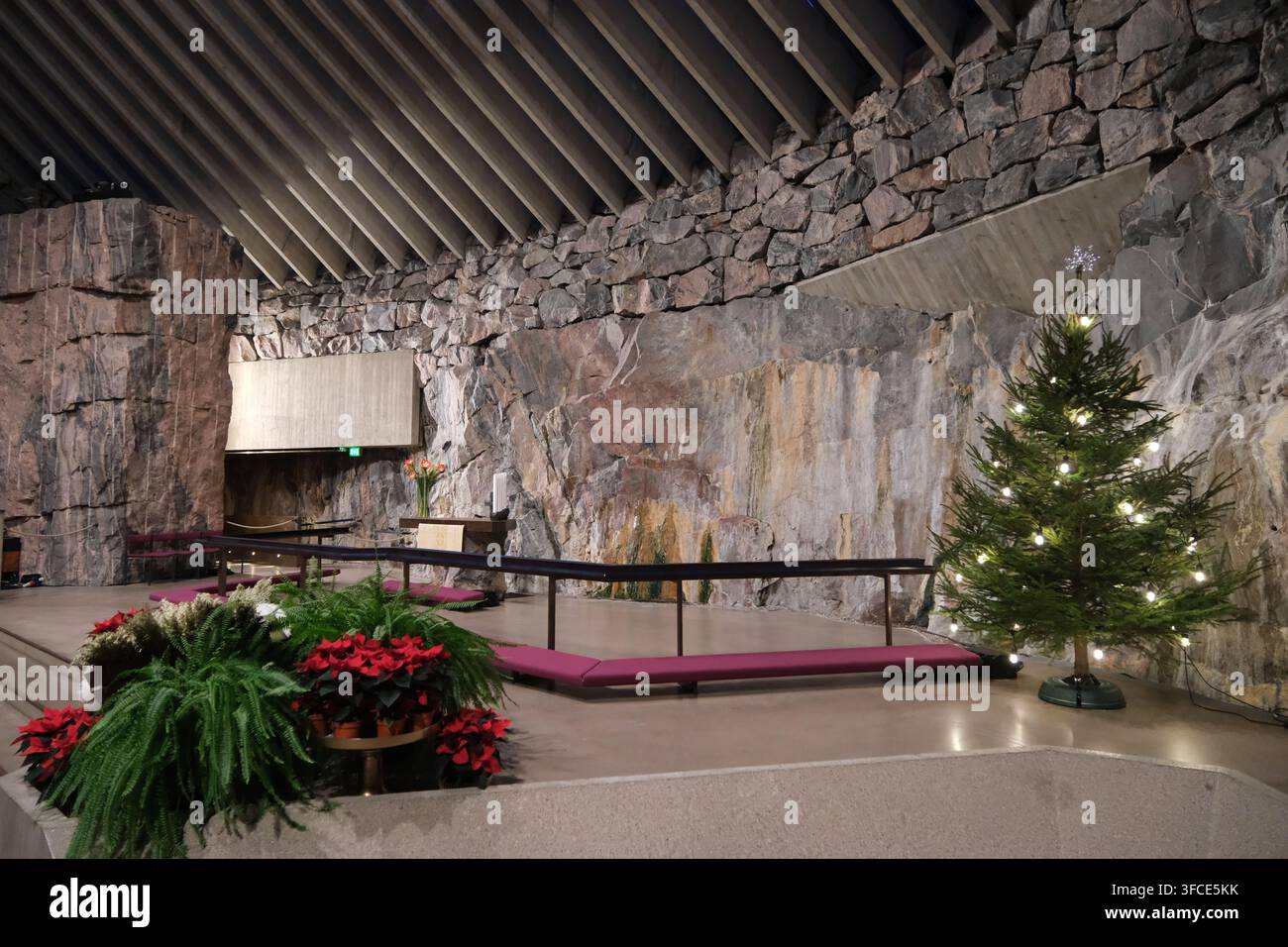 Helsinki, Finlandia-30 nov. 2025: altare principale decorato con un albero di Natale e fiori nella chiesa Temppeliaukio (chiesa di pietra), Helsinki, Finlandia Foto Stock