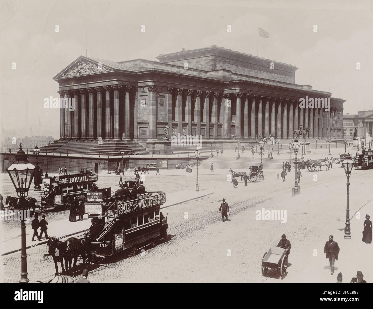 Hall Liverpool, Veduta di St George's Place e St George's Hall a Liverpool, fotografia, iscrizione: 'Liverpool', Liverpool, 1880 - 1910, fotografo, carta, cartone, carta baritata, stampa argentica al collodio alla luce del giorno, altezza 244 mm x larghezza 315 mm, quadrato, circo, sala da concerto, St George's Hall. Un grande edificio in pietra neoclassico con una lunga facciata colonnata e una larga scalinata davanti domina la scena, sormontato da un frontone scolpito e una bandiera sul tetto. Diversi lampioni si ergono lungo la strada e in cima agli ampi gradini, mentre alcune statue sono posizionate vicino all'edificio e su Foto Stock