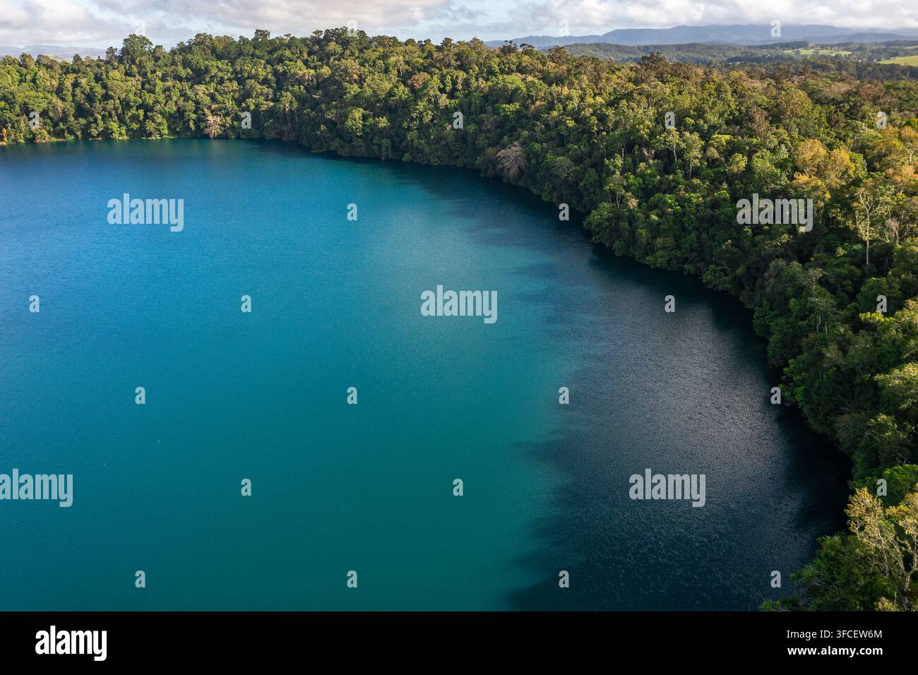 Vista aerea delle acque blu profonde del Lago Eacham circondate da una fitta foresta tropicale nel cratere di un vulcano spento nelle Atherton Tablelands Foto Stock