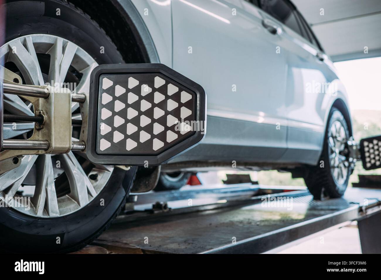 Bersaglio per l'allineamento delle ruote computerizzato su pneumatico SUV in officina, misurazione di precisione di pendenza, inclinazione e sterzata per la calibrazione della sospensione e la prevenzione dell'usura dei pneumatici. Foto Stock