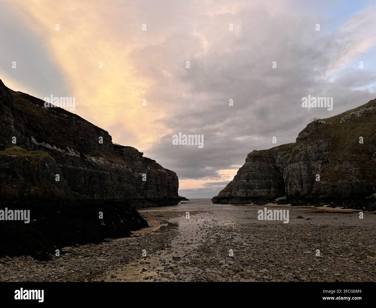 Imponenti scogliere rocciose incorniciano un'apertura verso il mare sotto nuvole pastello della sera vicino alla grotta di Smoo a Durness nelle Highlands scozzesi. - Immagine stock catturata con smartphone
