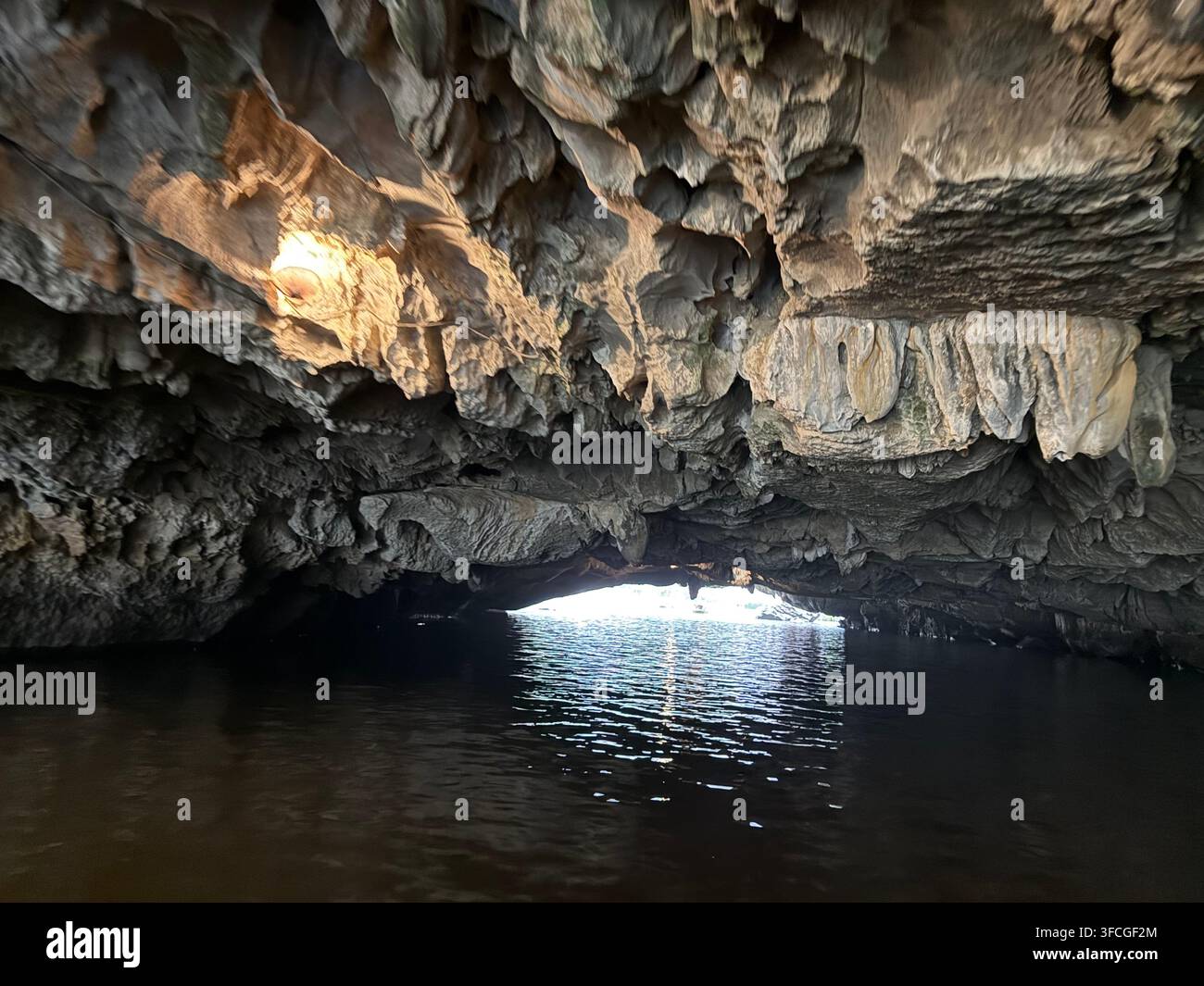 Sotto un soffitto molto basso della prima grotta bassa - Ca Cave (Hang Ca) sul fiume Ngo Dong che si snoda tra i campi di riso e le ripide colline calcaree - Immagine stock catturata con smartphone