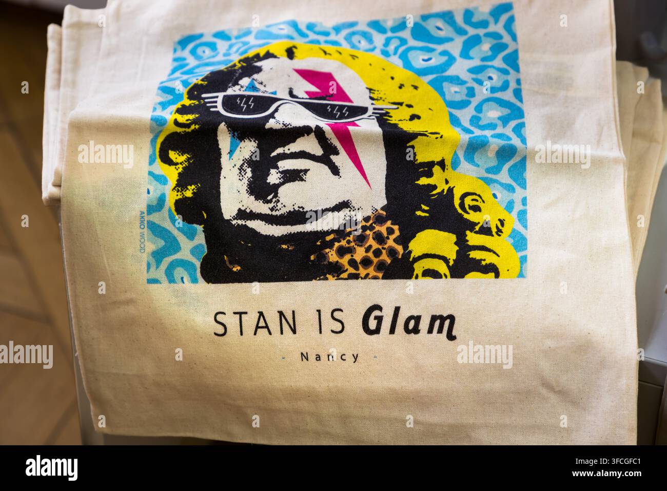 Una borsa di tela con un ritratto ispirato a David Bowie e lo slogan "Stan è Glam – Nancy" giace in un negozio di souvenir su Place Stanislas a Nancy, Grand Est, Francia. Il gioco di parole collega il nome del re Stanislas allo stile glam-rock del musicista britannico. Foto Stock