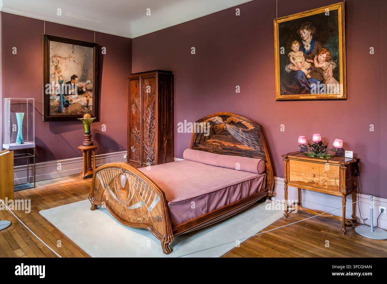 Un letto Art Nouveau elaboratamente intagliato con un motivo a libellula si trova in una sala espositiva in stile camera da letto al Musée de l'École de Nancy in Rue du Sergent Blandan a Nancy, Grand Est, Francia, circondato da dipinti a figura intera e un armadio intagliato. Foto Stock