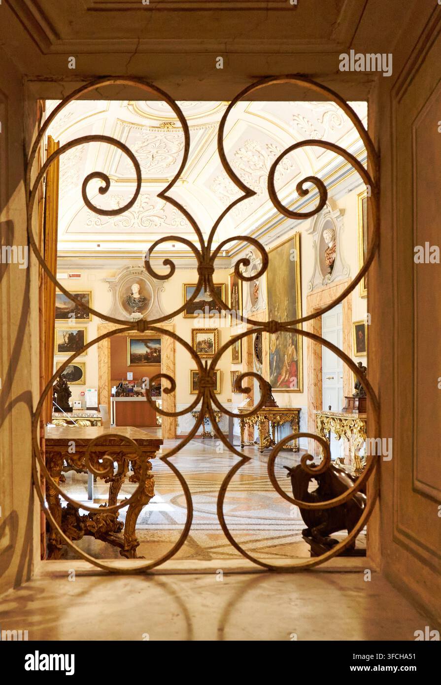 Roma, Italia - 17 giugno 2026: Interno della lussuosa villa storica Farnesina visibile attraverso una grata ornata, con opere d'arte classiche, mobili eleganti, un Foto Stock