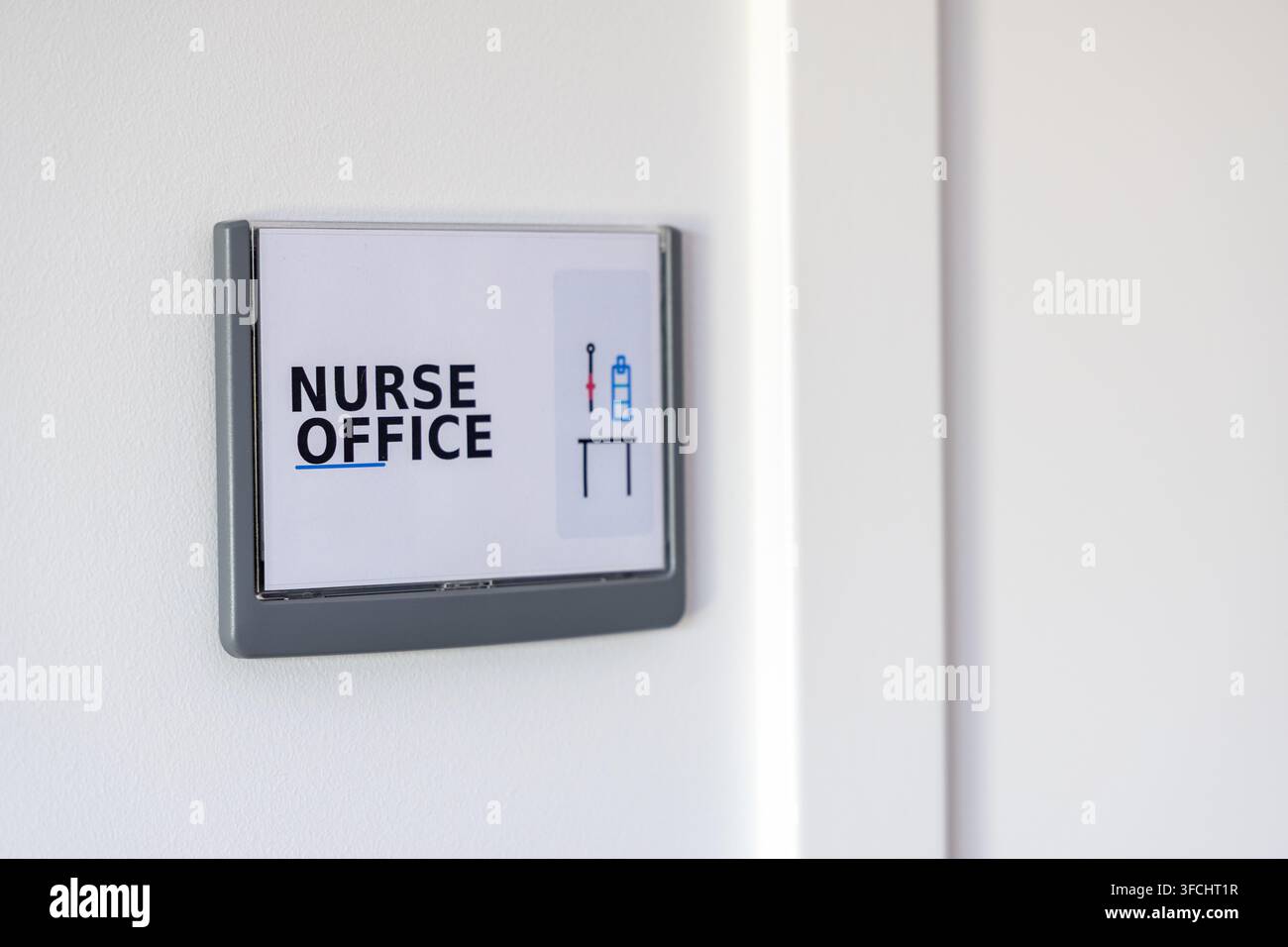 Un segnale chiaro che indica la posizione dell'ufficio delle infermiere, con icone semplici per le forniture mediche e una scrivania Foto Stock