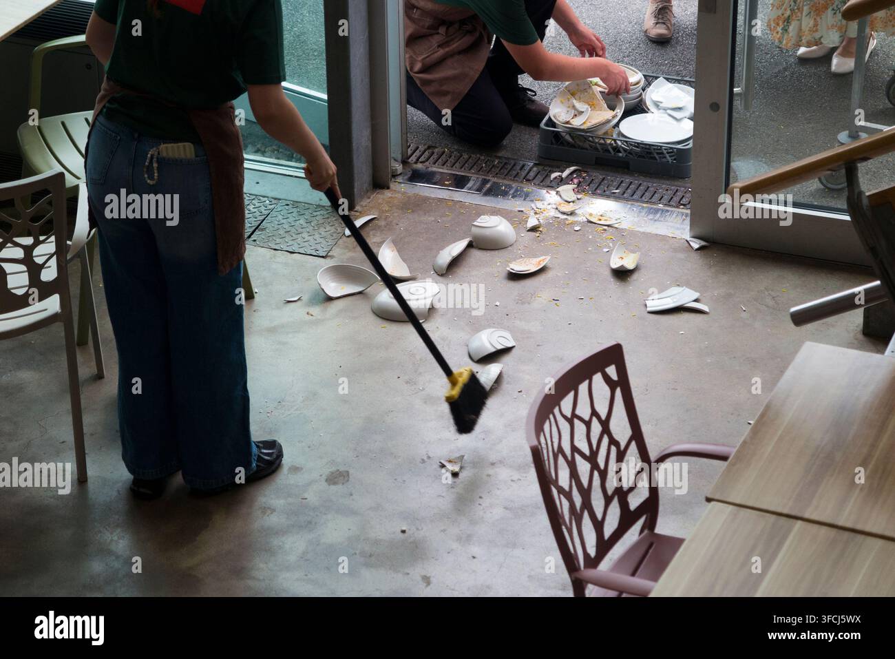 Personale / cameriere che raccoglie piatti e stoviglie di ceramica rotti, stoviglie cadute accidentalmente da un carrello in un incidente di caffè / ristorante. Regno Unito (150) Foto Stock