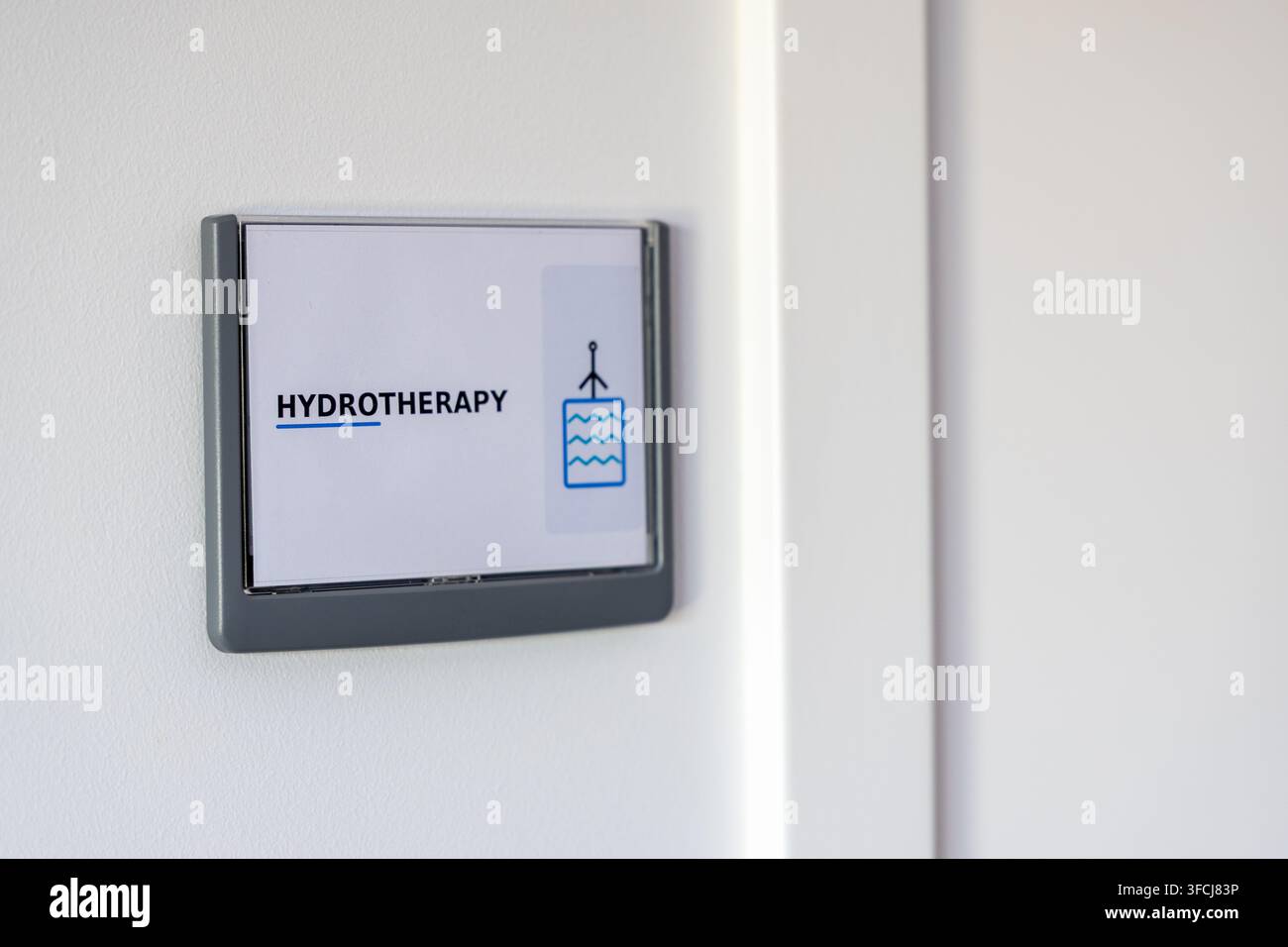 Un semplice cartello su un muro indica una stanza dedicata all'idroterapia, con testo e un'icona legata all'acqua Foto Stock