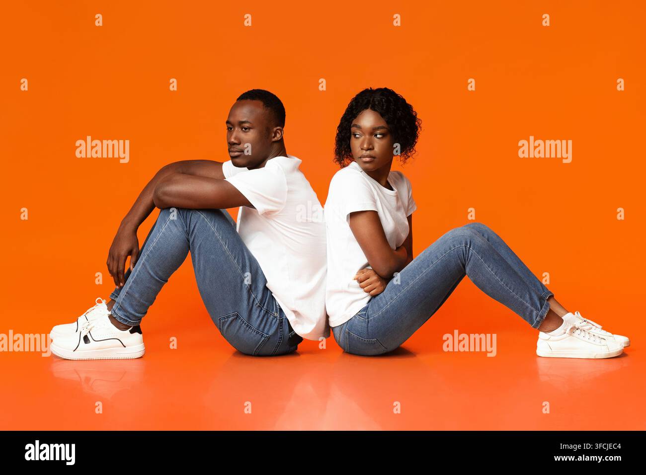 Difficoltà nel matrimonio. Giovane donna afroamericana arrabbiata che guarda il suo fidanzato triste, coppia nera che litiga, seduti insieme per terra, sentono Foto Stock