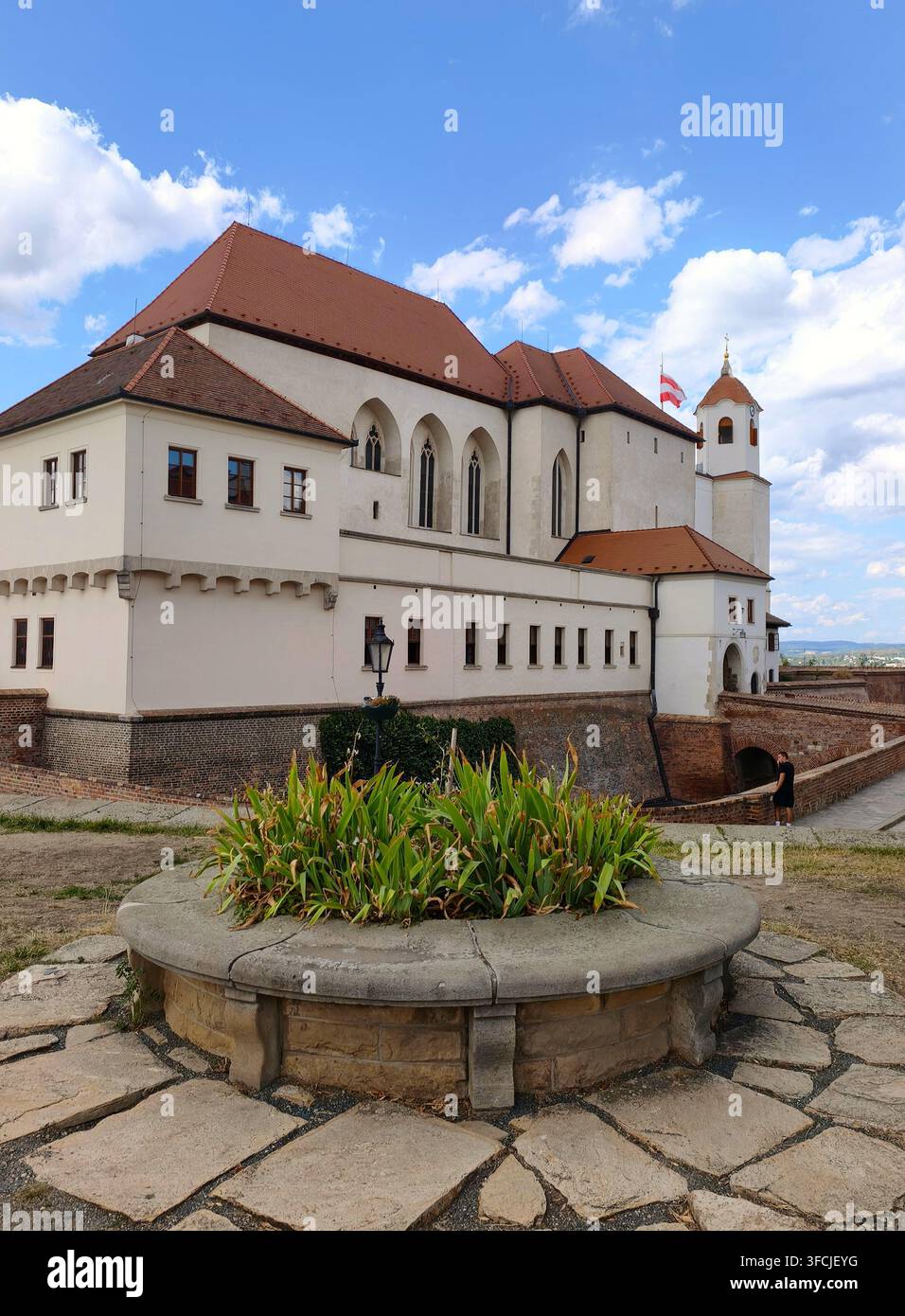 Una vista della storica fortezza del castello di Spilberk con un aiuola di pietra in primo piano sotto un bel cielo estivo con nuvole bianche a Brno, Moravia - Immagine stock catturata con smartphone