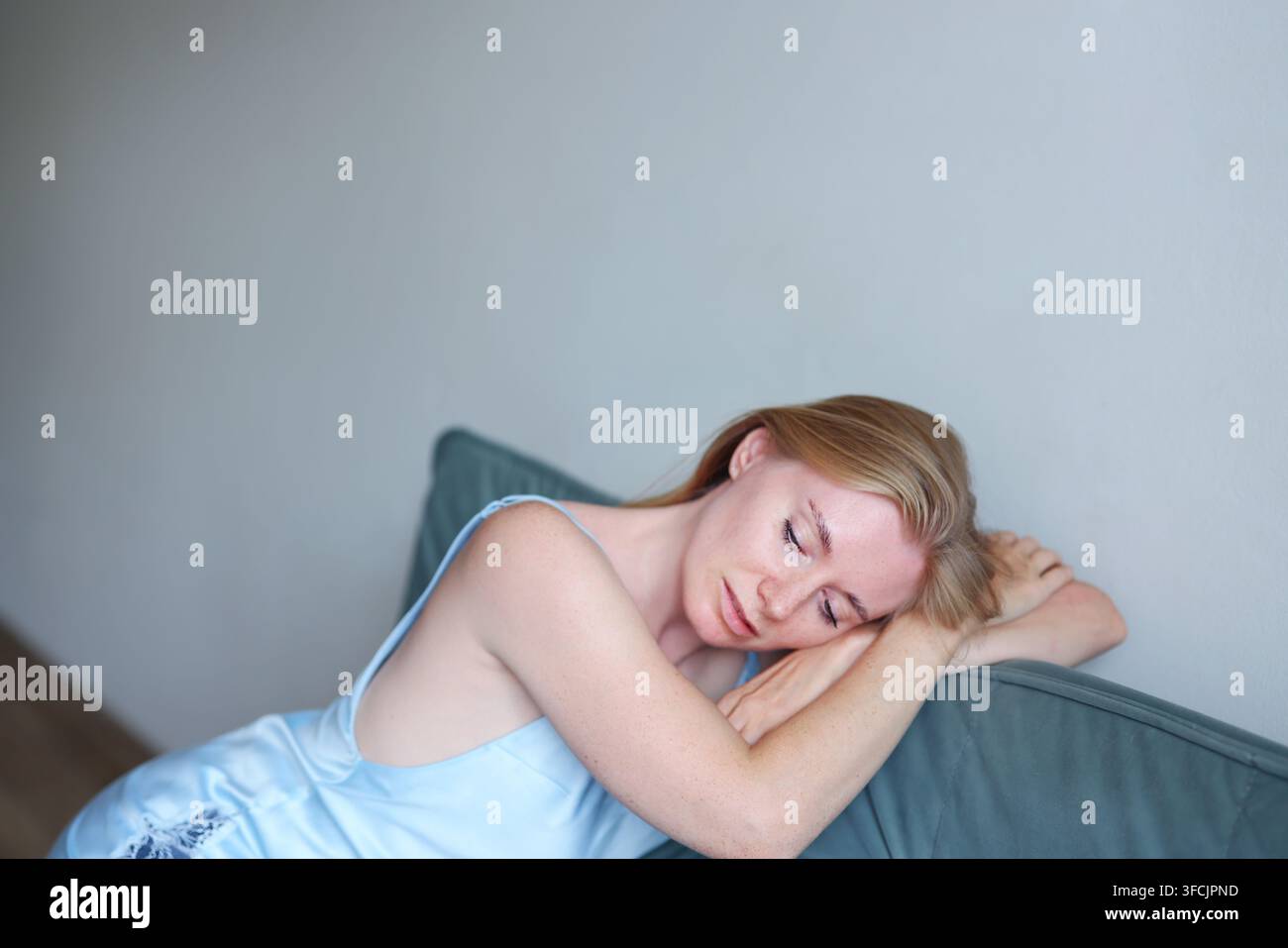 Donna bionda felice con lentiggini naturali che si rilassa in interno, umore positivo, fiducia e concetto di bellezza quotidiana. Foto Stock