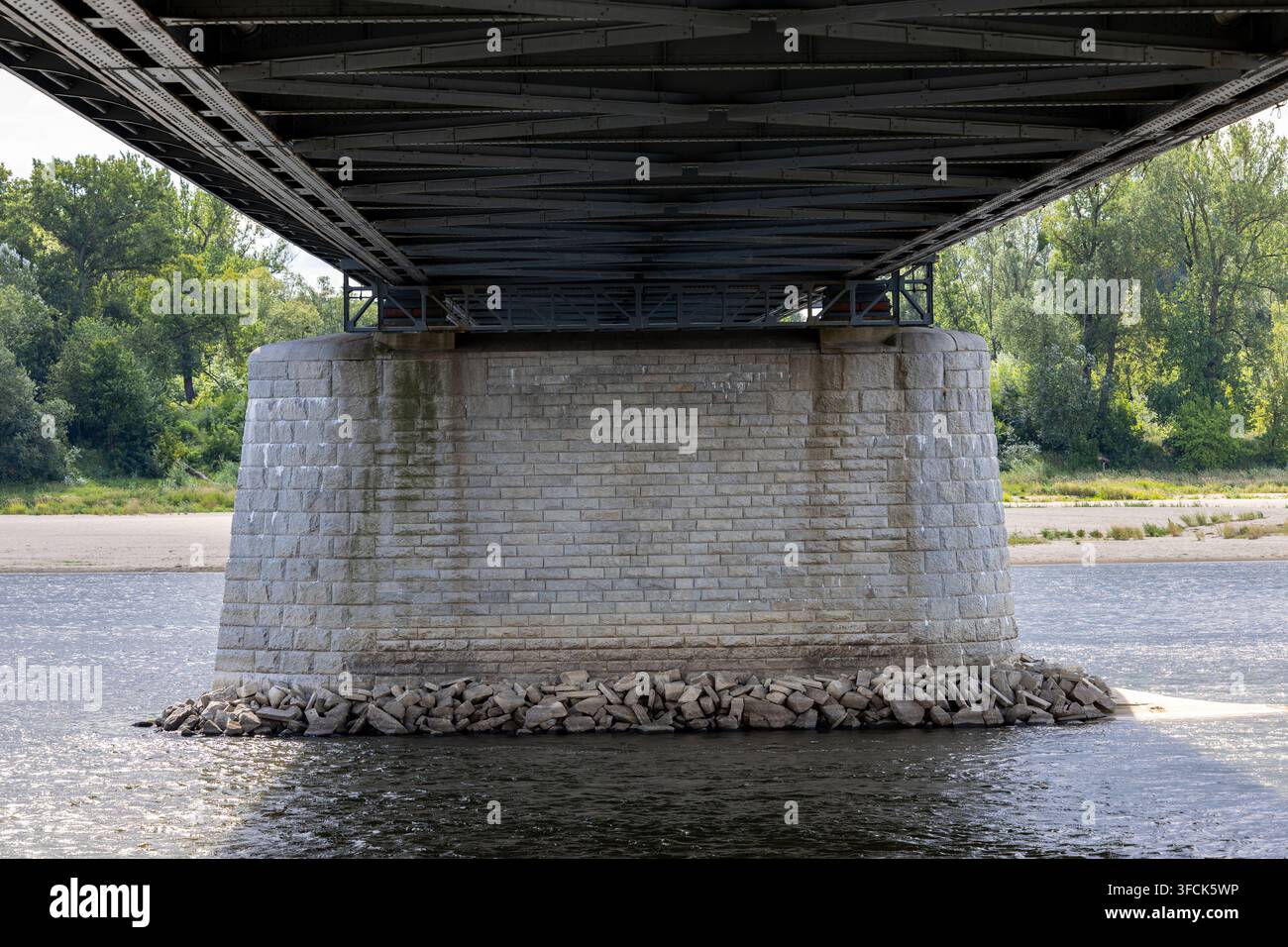 Pilo di ponte in un fiume. Blocchi di pietra formano il supporto. Travi d'acciaio corrono sotto la parte inferiore del ponte. Il riprap copre la sezione inferiore. Foto Stock